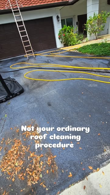 Roof cleaning setup with hoses laid across a driveway.